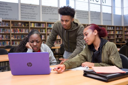 Group of high school students at computer in library