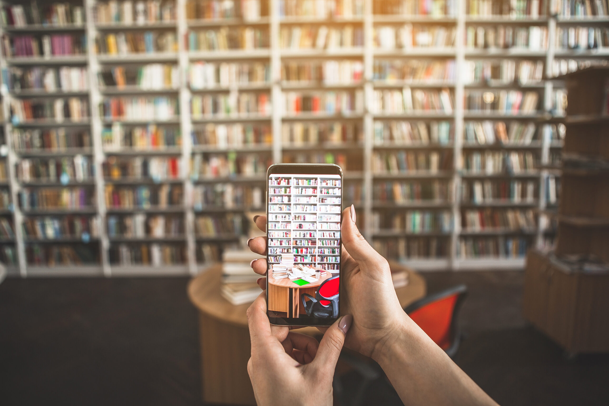 Woman arms making picture of volumes Close up female hands holding mobile. She taking photo of table with books in library