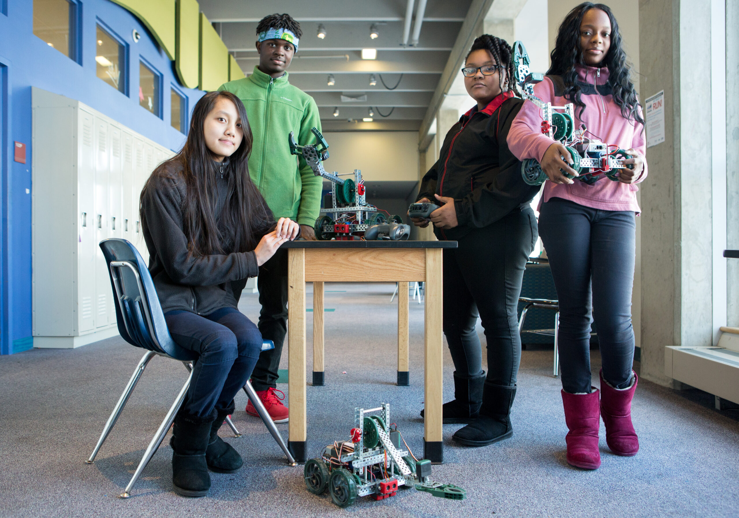 Group of high school students in hallway with robots Students from MC2 STEM High School show off the robots they built in class.